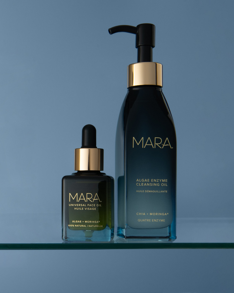 MARA Universal Face Oil and Algae Enzyme Cleansing Oil on a glass shelf on a blue background
