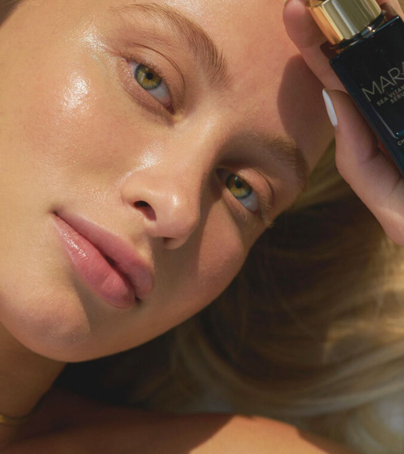 Model holding Sea Vitamin C Serum up by forehead