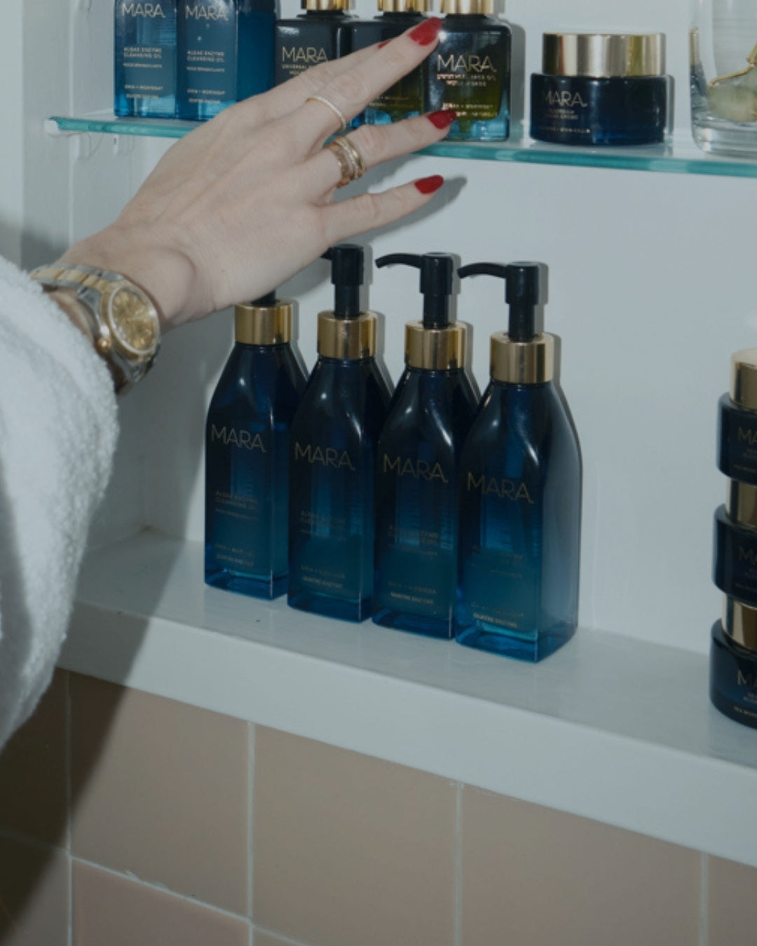 Hand reaching inside medicine cabinet with Algae Enzyme Cleansing Oil inside