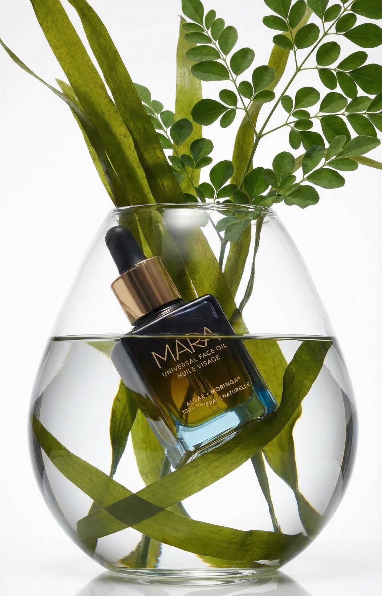a leaf vase with universal face oil floating in the vase