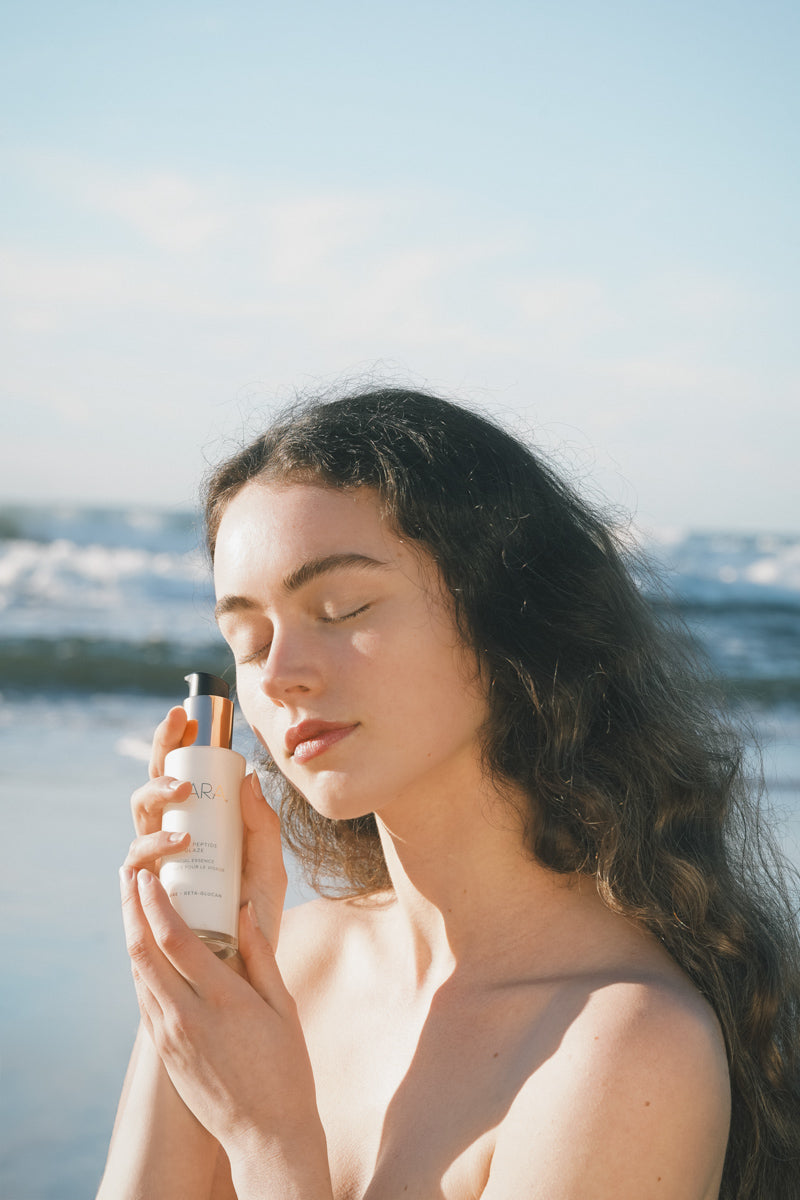 woman holding Pearl Peptide Glaze in front of ocean
