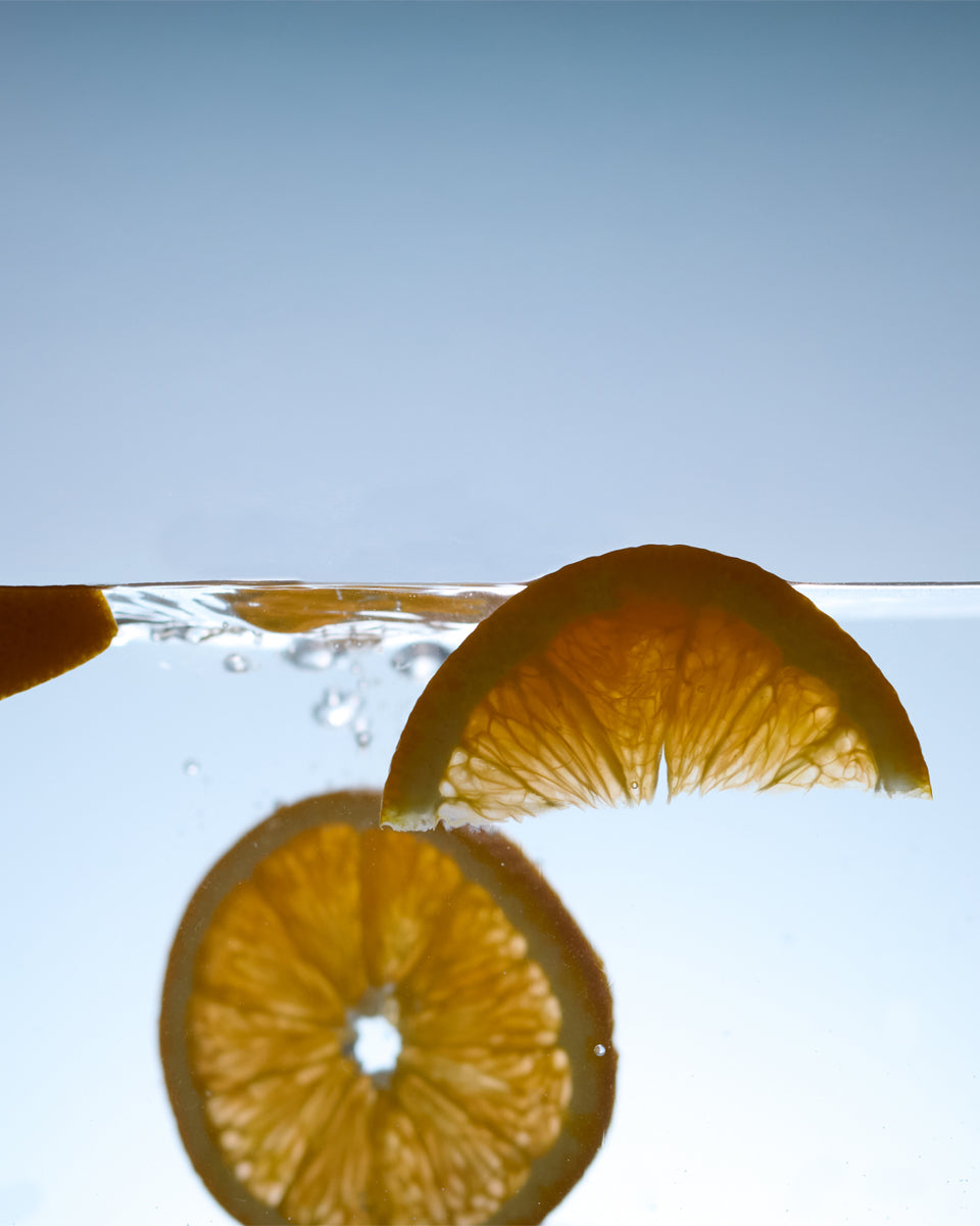 Orange slices floating on water with a clear blue background