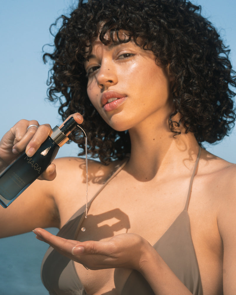 Girl pumping Algae Enzyme Cleansing Oil into hand