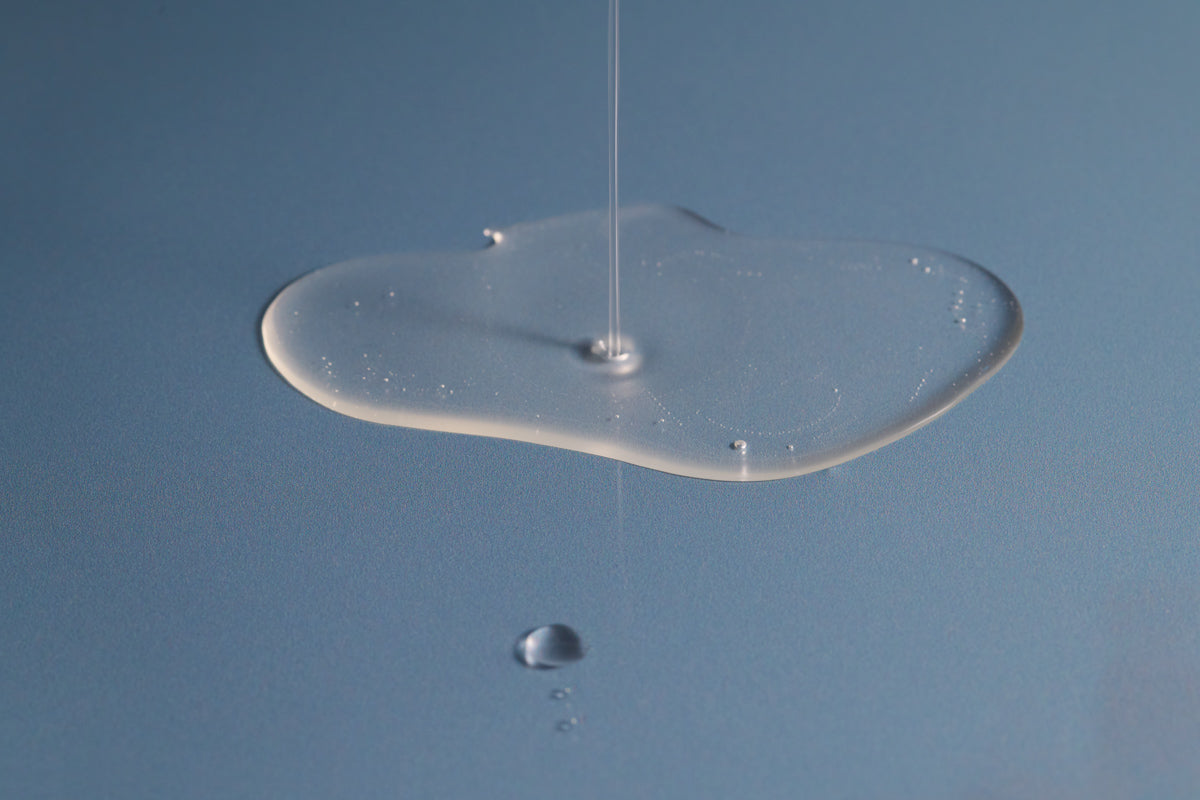 swatch of Algae Enzyme Cleansing Oil dripping on blue surface