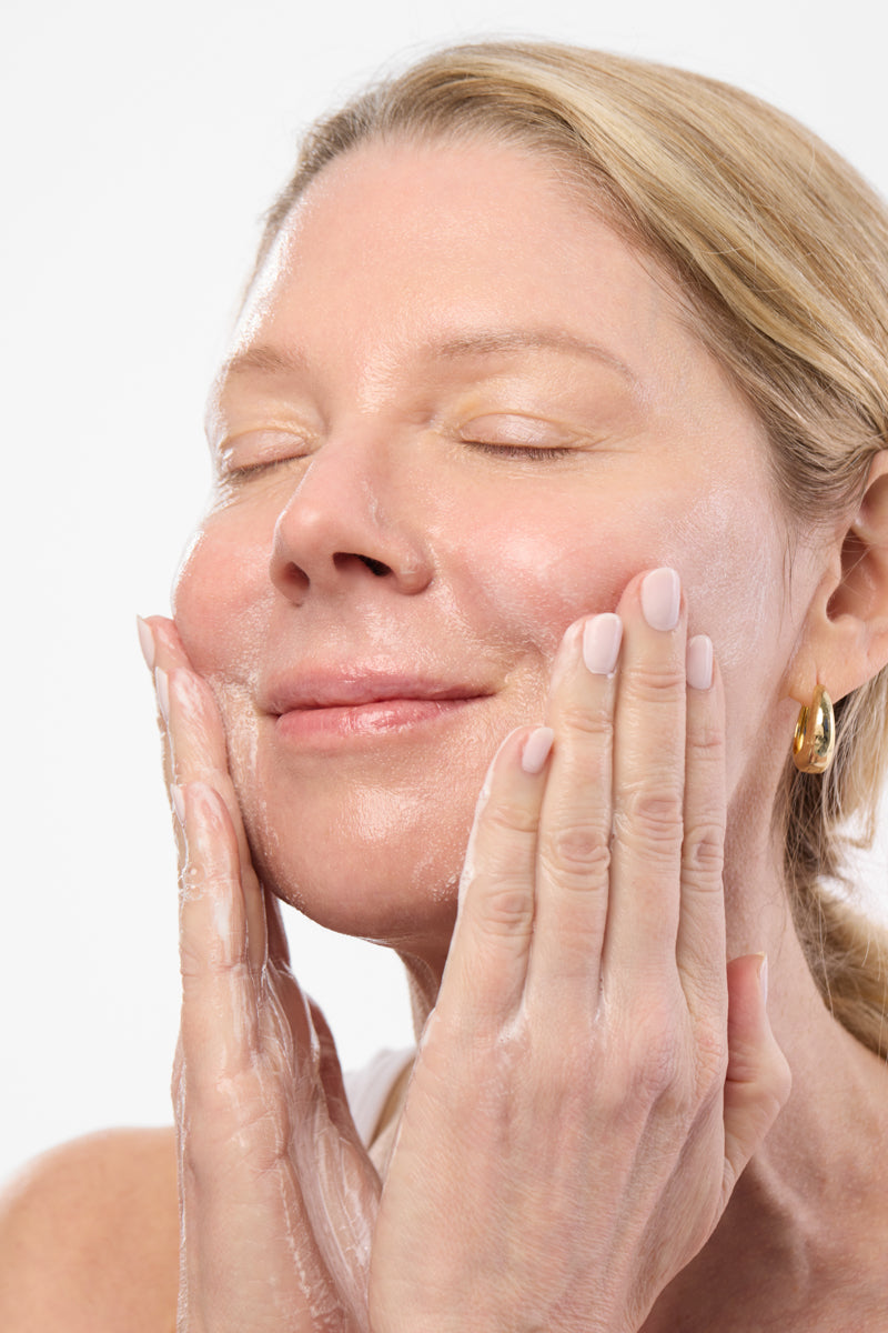 woman applying Aura Cleanse Foaming Gel Cleanser to face