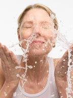 Woman splashing water on her face with a white background