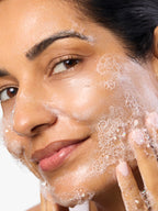 woman applying Aura Cleanse Foaming Gel Cleanser to face