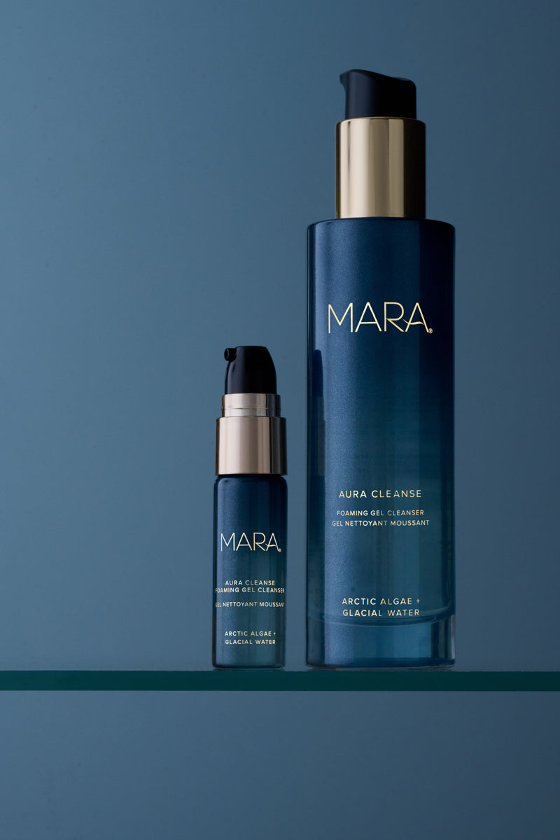 Two sizes of Aura Cleanse Foaming Gel Cleanser on glass shelf with blue background