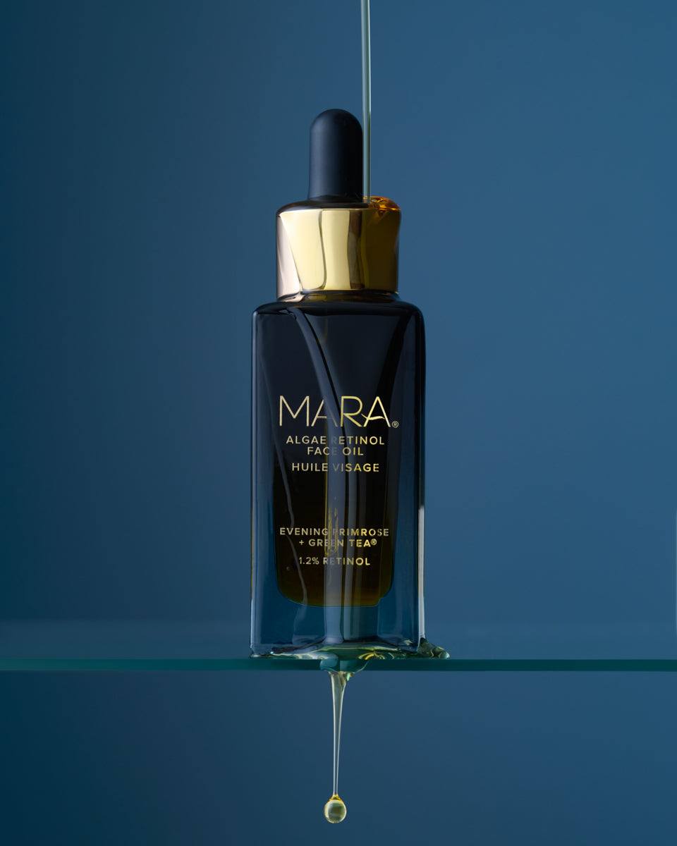 MARA Algae Retinol Face Oil bottle with a drop of oil on a glass shelf with blue background