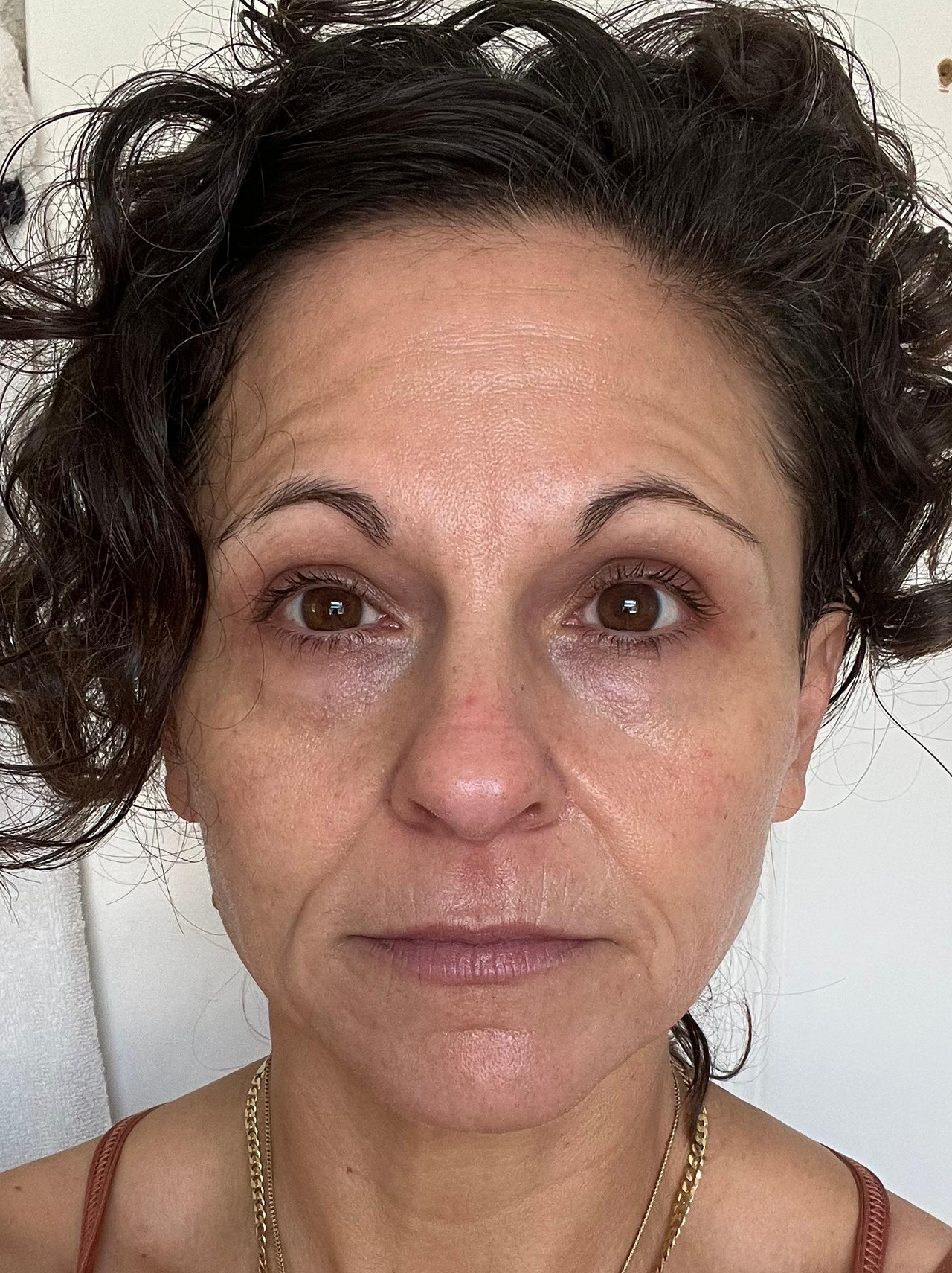 Close-up of a person with dark hair and a neutral expression against a plain background