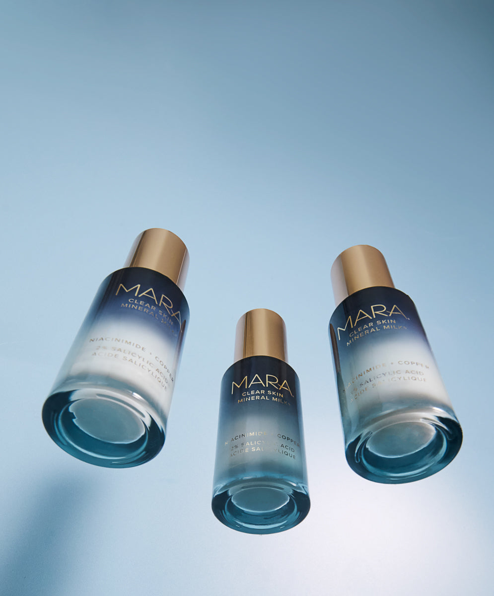 Three bottles of Clear Skin Mineral Milk on a gradient blue background