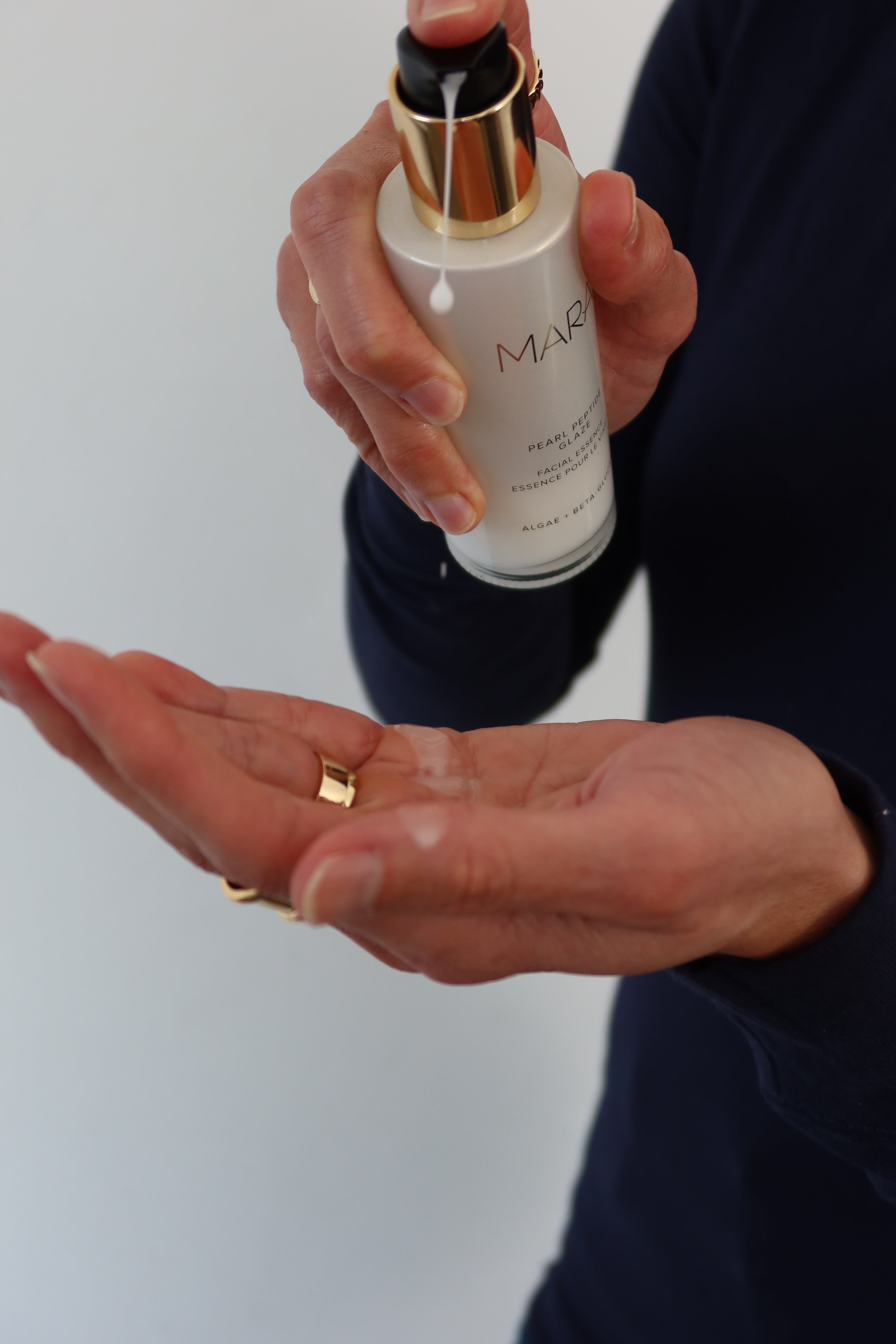 Close shot of model squirting Pearl peptide product into her hand 