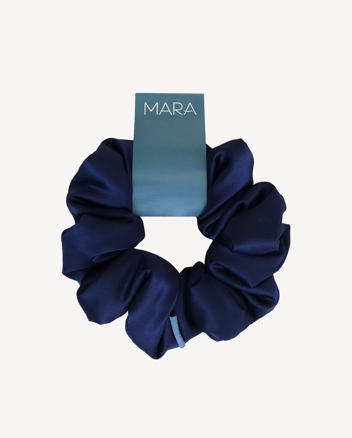 Navy blue scrunchie with a 'MARA' branded card on a white background