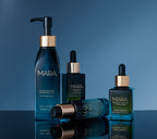 Cleansing Oil, Flower Acid, Retinol Oil, and Universal Oil on a reflective surface with a blue gradient background