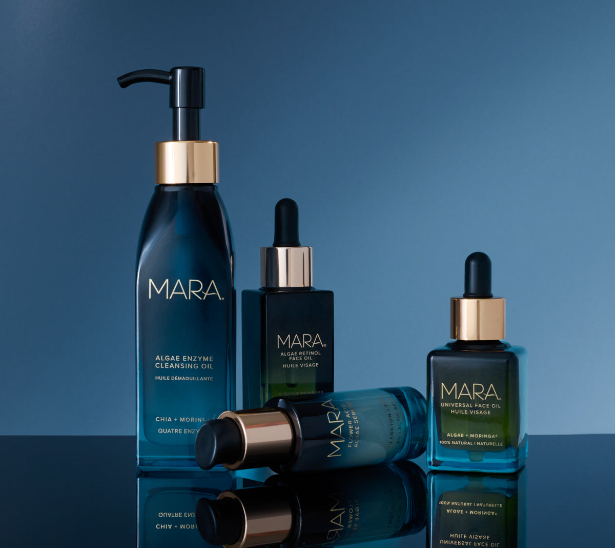 Cleansing Oil, Flower Acid, Retinol Oil, and Universal Oil on a reflective surface with a blue gradient background