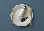 the mara essentials duo with pearl peptide glaze and universal face oil on a white dinner plate with utensils