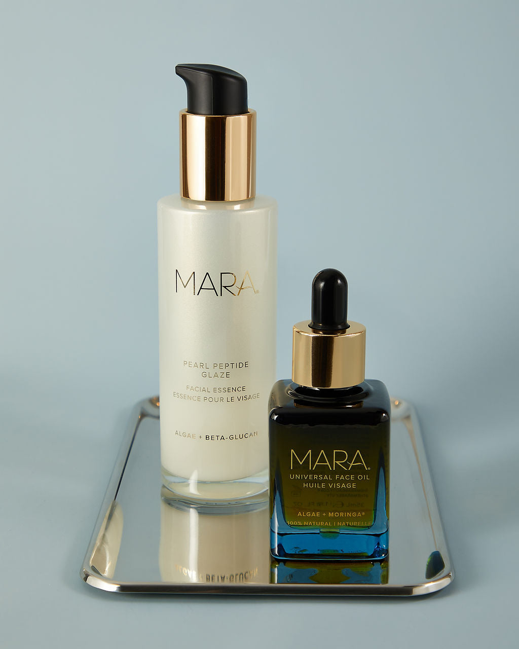 the mara essentials duo with pearl peptide glaze and universal face oil on silver tray with blue background