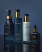 Algae Enzyme Cleansing Oil, Aura Cleanse Gel Cleanser, Pearl Peptide Glaze, and Universal Face Oil on blue reflective surface