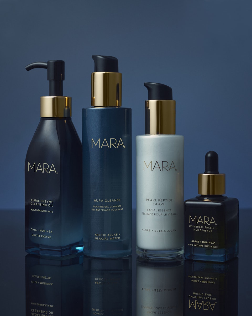 Algae Enzyme Cleansing Oil, Aura Cleanse Gel Cleanser, Pearl Peptide Glaze, and Universal Face Oil on blue reflective surface