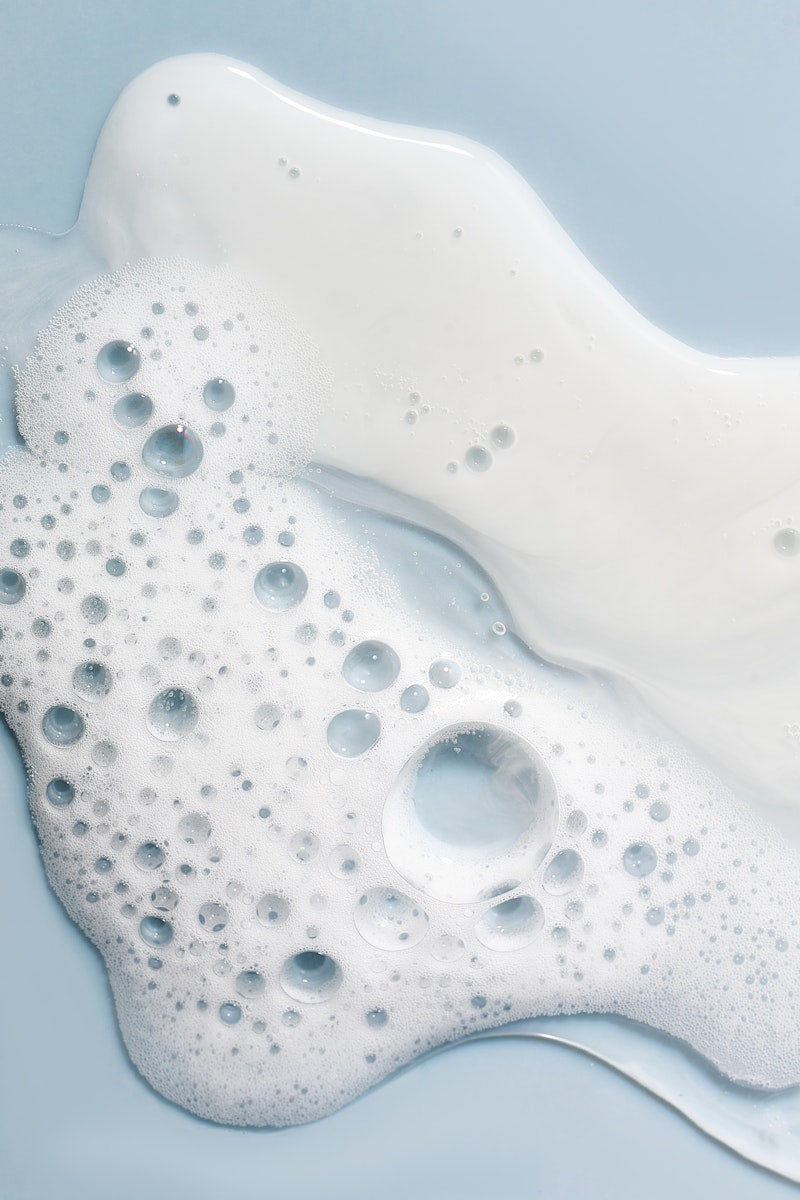 Aura Cleanse and Pearl Peptide swatches on light blue surface