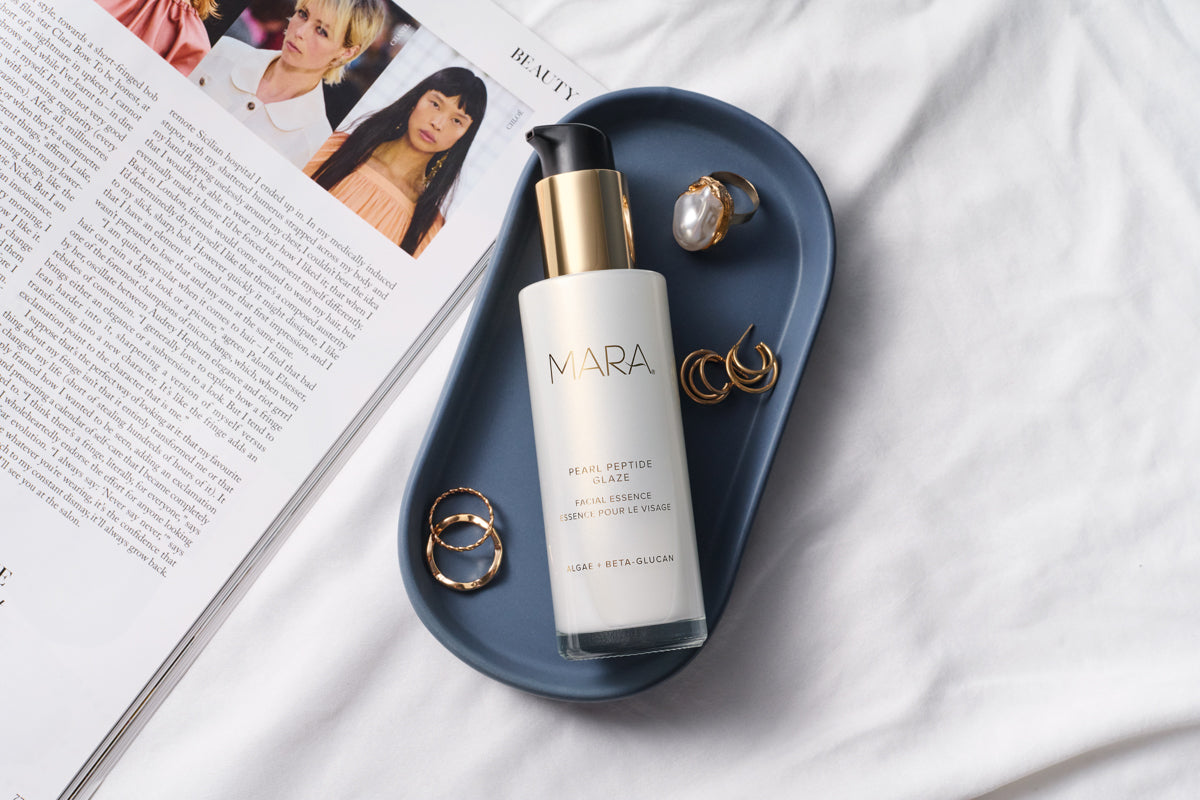 Bottle of Pearl Peptide on a tray with jewelry next to a magazine