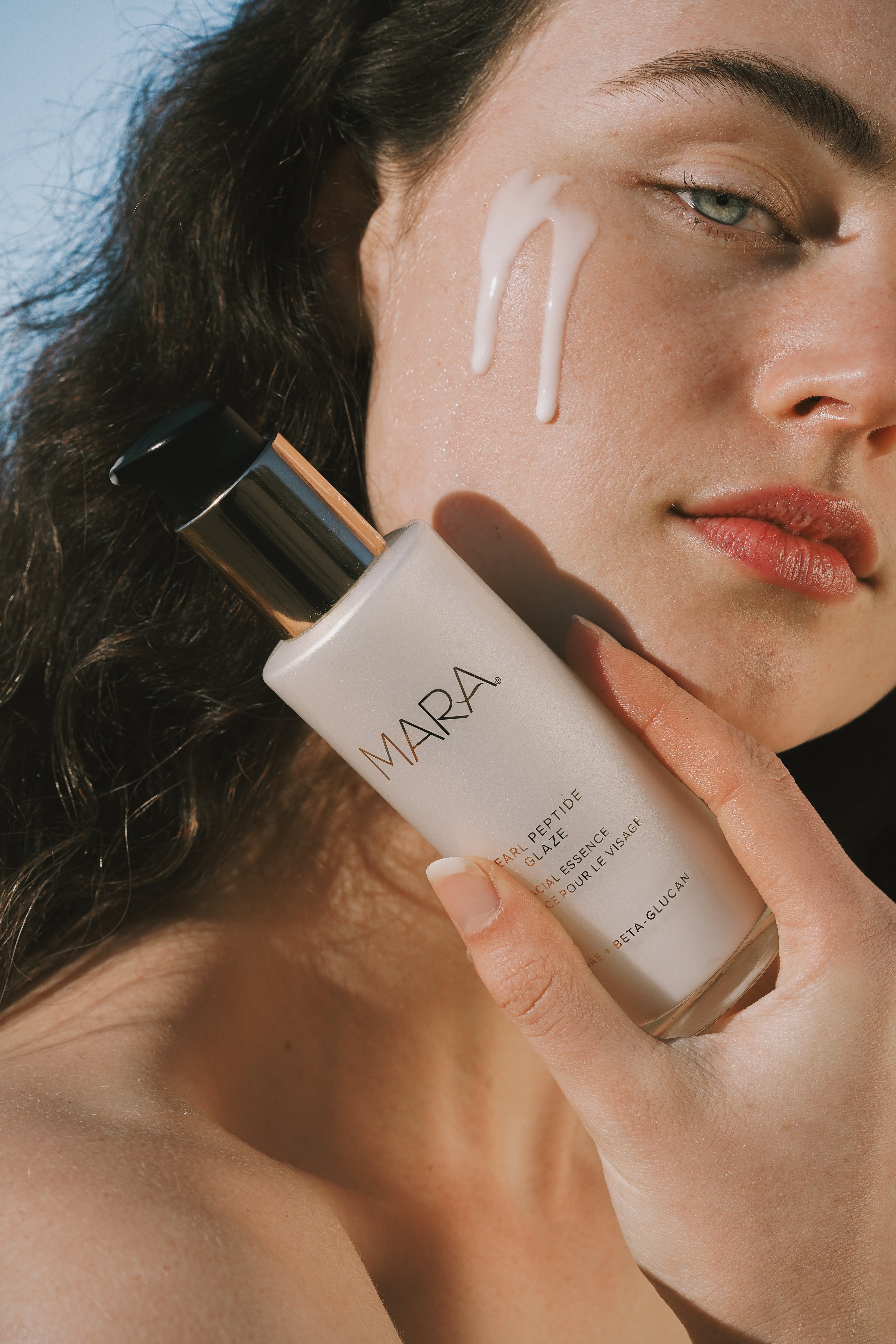 Person holding Pearl Peptide Glaze with a close-up of their face.