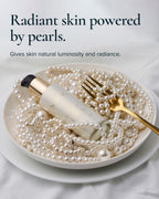 Pearl Peptide Glaze lies on a bed of pearls inside a white bowl, with a gold fork resting on top. Text at the top reads, 'Radiant skin powered by pearls.