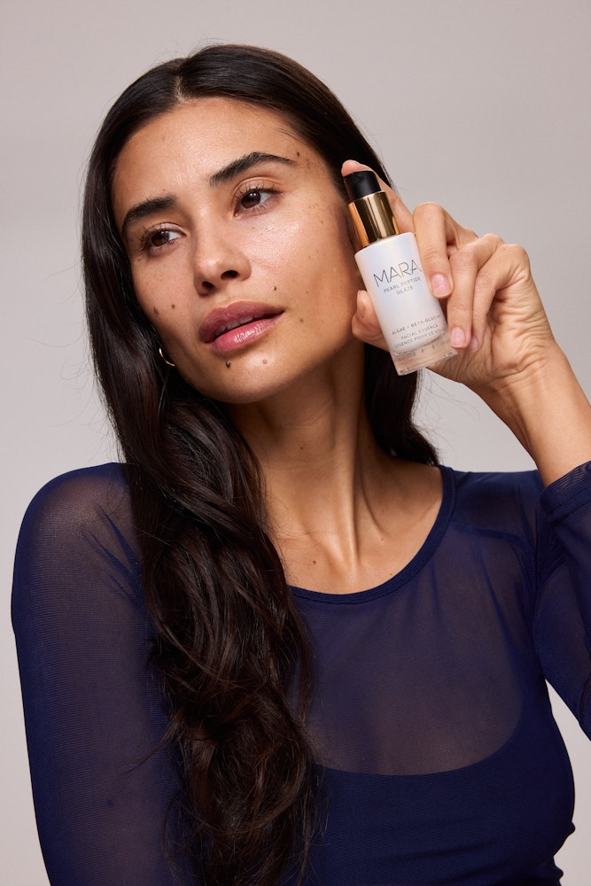 Woman holding MARA Pearl Peptide Glaze 30mL by her face 