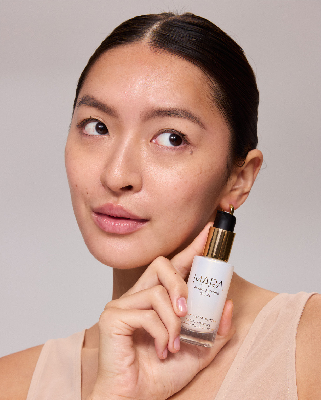 Woman holding a Mini Pearl Peptide Glaze with a neutral background