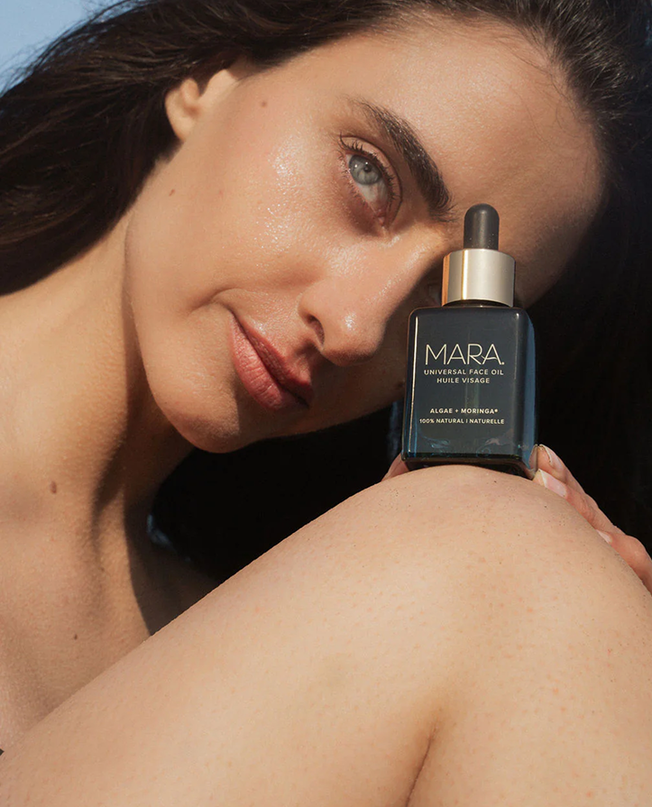 person holding Universal Face Oil on knee