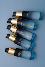 multiple bottles of Sea Kale Sunscreen Serum on a blue surface