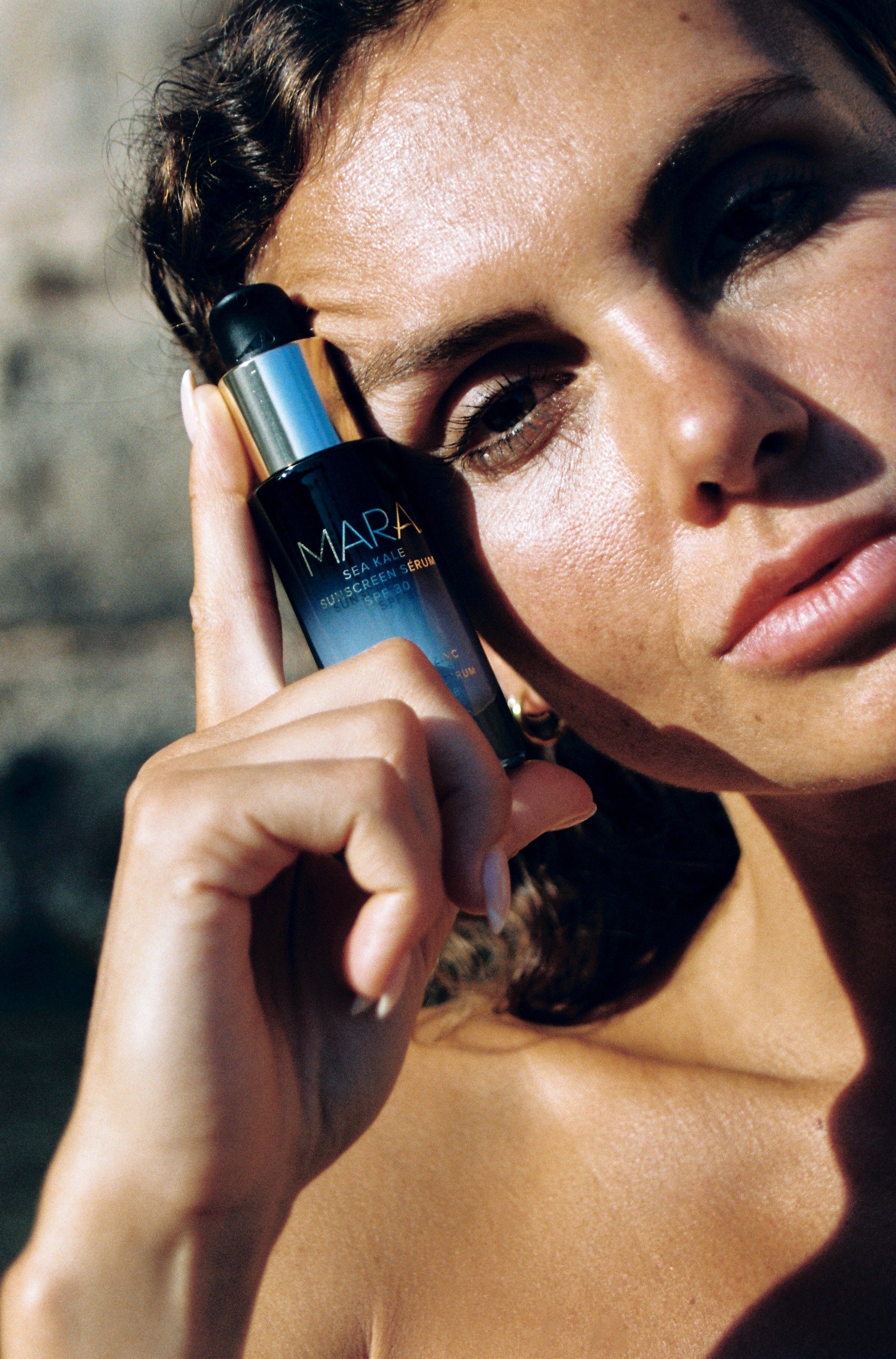 Woman holding MARA Sea Kale Sunscreen to her face 