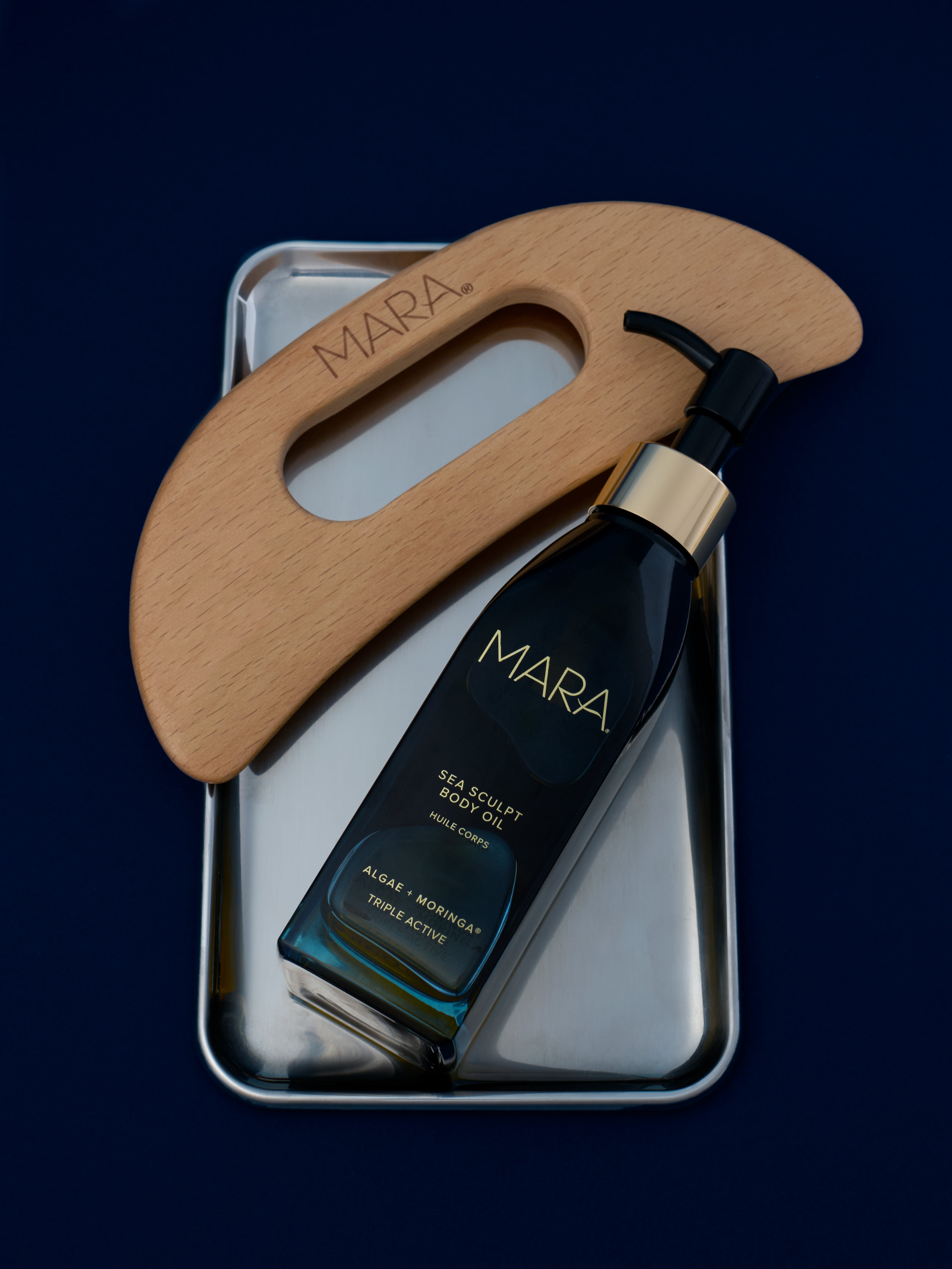 Sea Sculpt Body Oil and Body Tool on silver tray on navy background