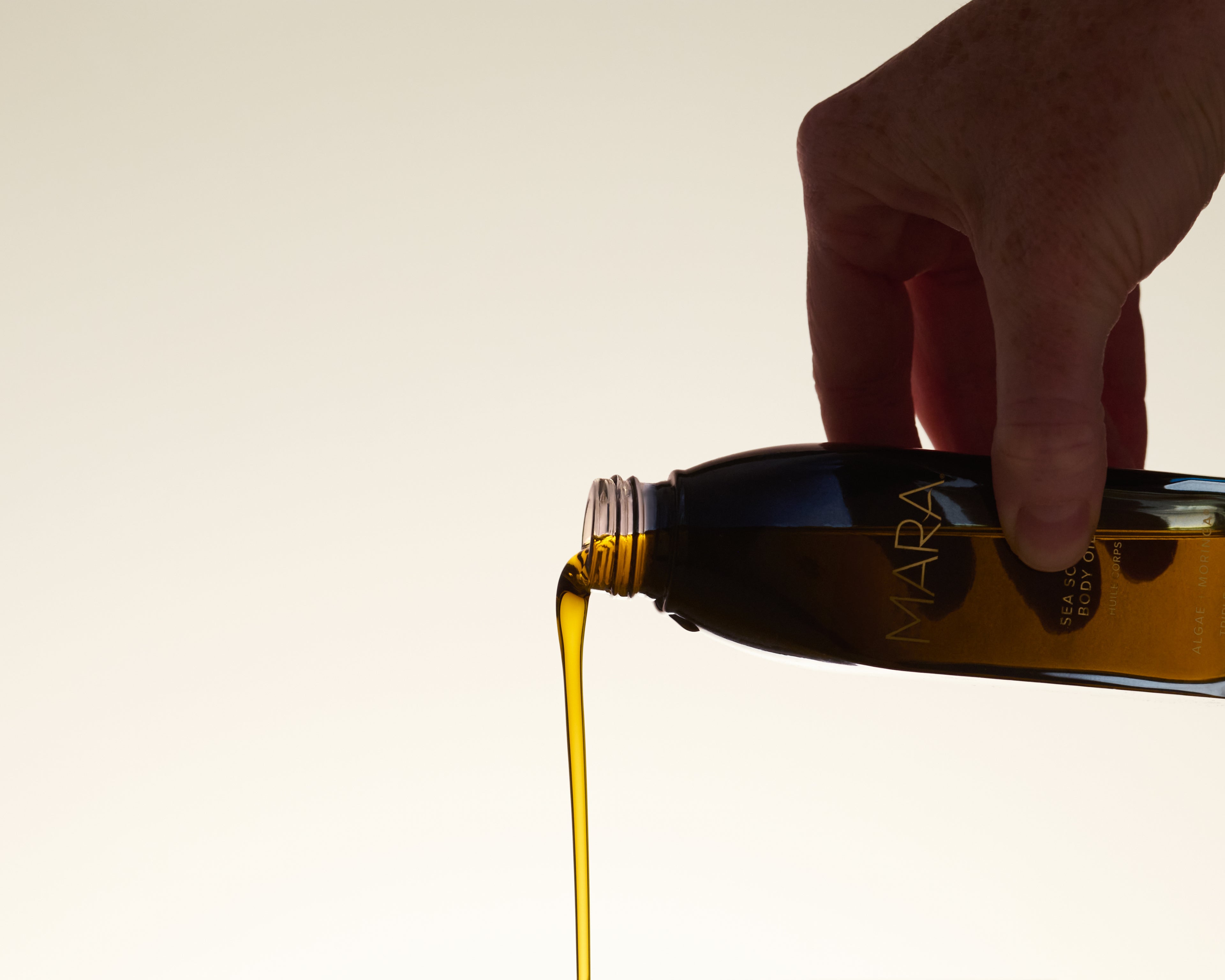 Hand tipping Sea Sculpt Body Oil and pouring it out