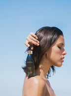 model holding sea sculpt body oil on shoulder