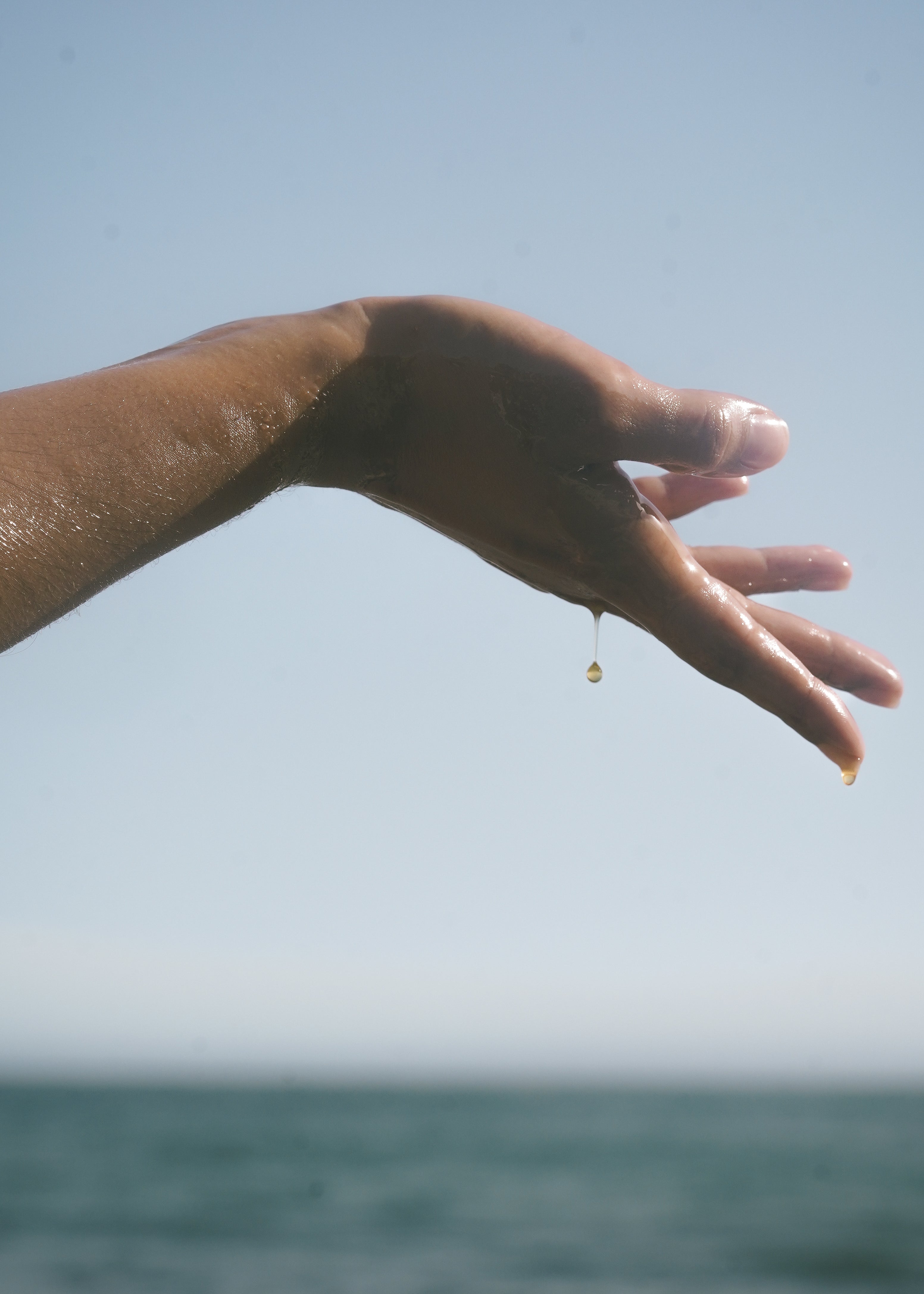 sea sculpt body oil dripping down arm and hand 