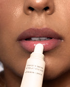Person applying Clear Sea Silk Lip Balm to their lips with a close-up focus on the action.
