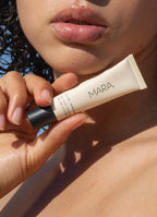 Hand holding a tube of Clear Sea Silk Lip Balm near a person's face.