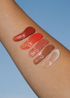 MARA Lip balm swatches on a person's arm against a blue background