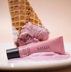 Nude Beach Sea Silk Lip Balm on a pink ice cream scoop with waffle cone in the background.