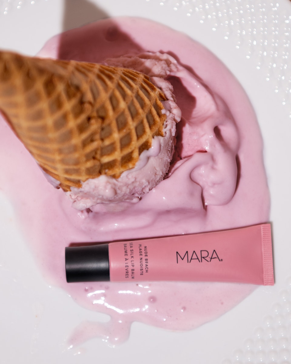 Nude Beach Sea Silk Lip Balm next to upside down strawberry ice cream cone