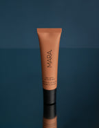 Sea Latte Sea Silk Lip Balm on a reflective surface against a dark blue background