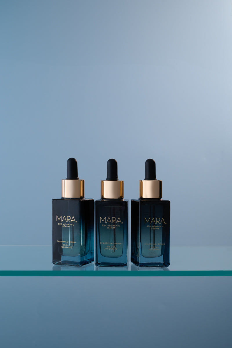 Three Sea Vitamin C Serum  bottles on a clear shelf against a light blue background