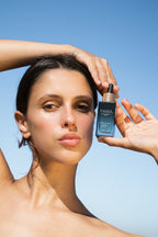 Woman holding Sea Vitamin C Serum  against a clear blue sky