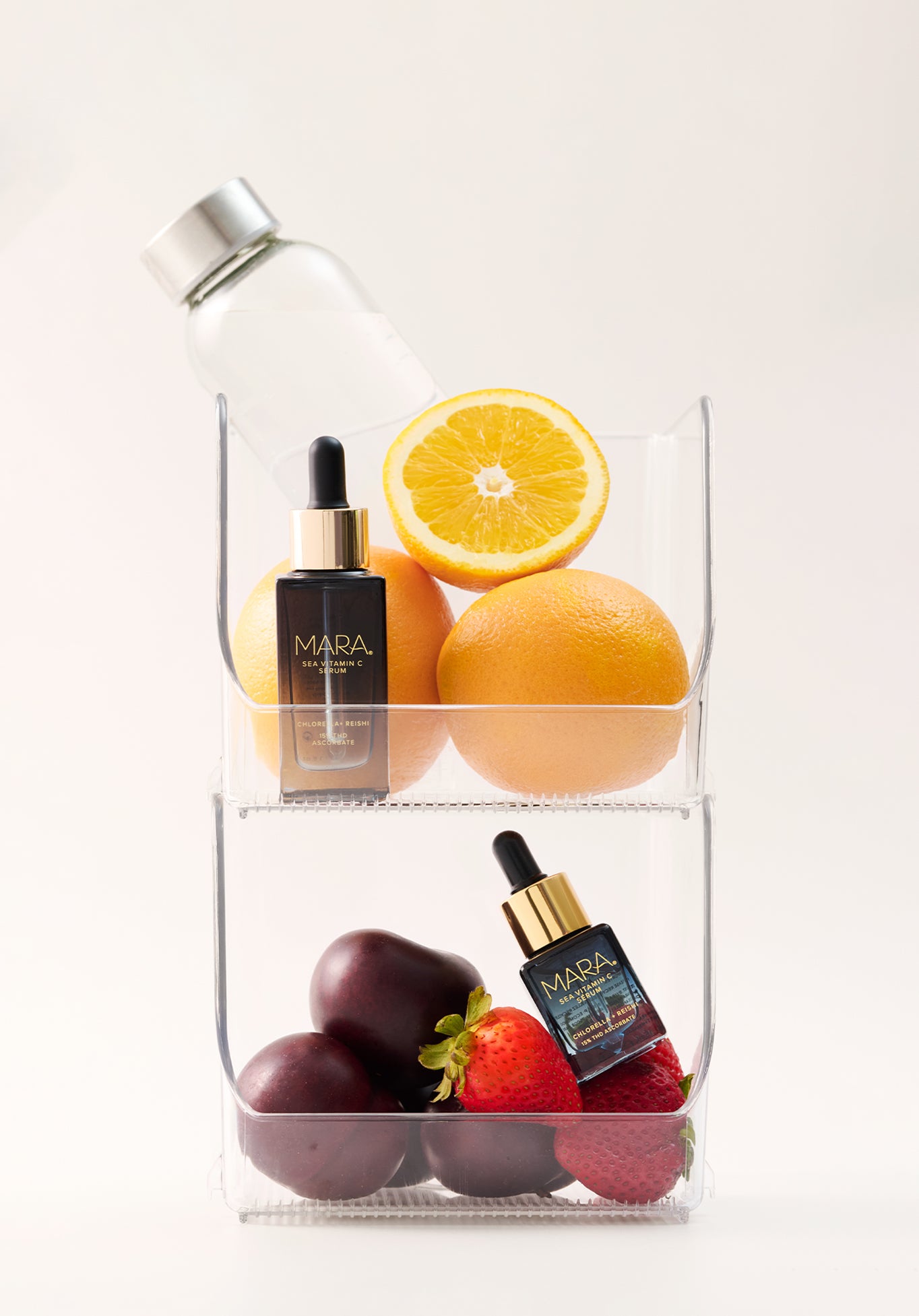 Clear plastic container with fruits and Sea Vitamin C Serum on a white background
