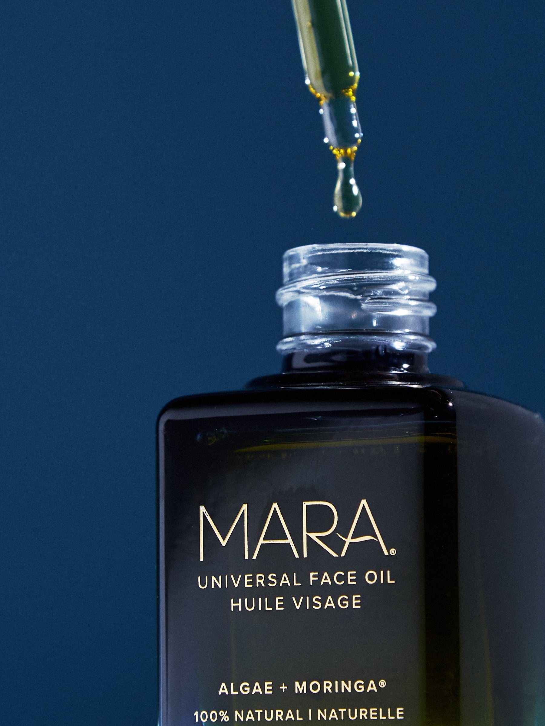 MARA universal face oil bottle with dropper on a dark blue background