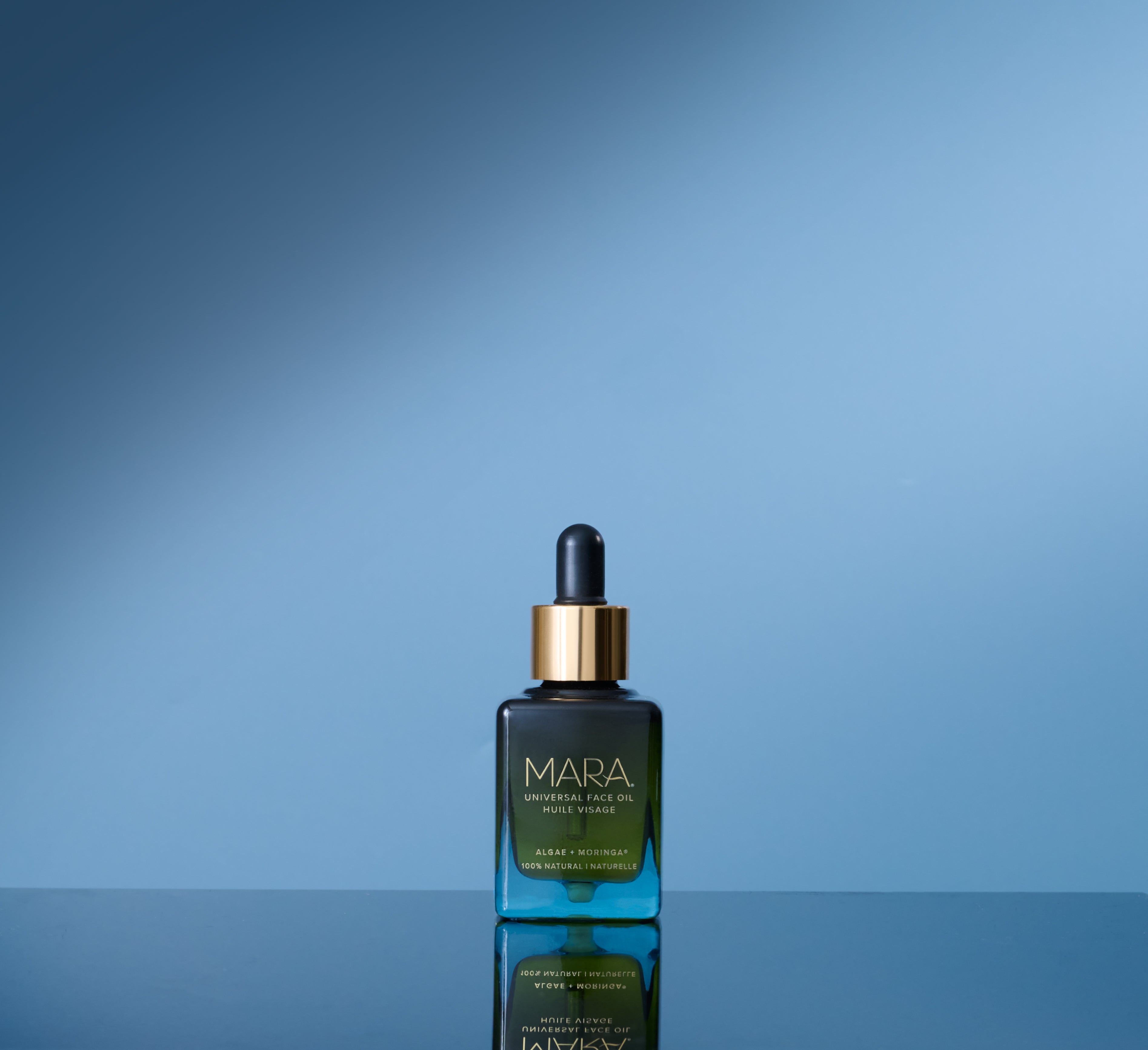 MARA Universal Face Oil on a reflective surface with a blue gradient background