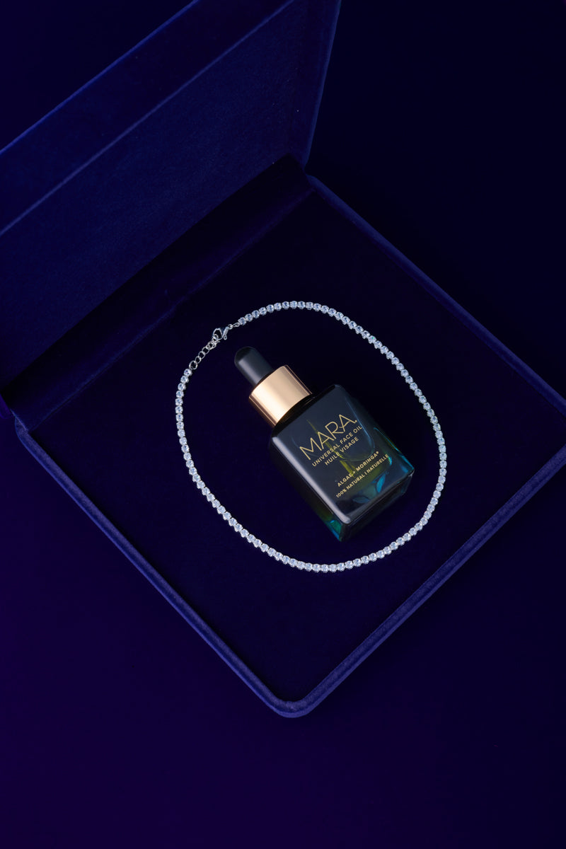 Universal Face Oil and diamond bracelet in a blue velvet jewelry box