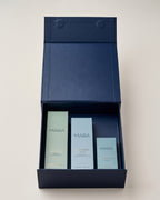A navy blue gift box opened to reveal Sea Sculpt Body Oil, Pearl Peptide Glaze, Universal Face Oil.