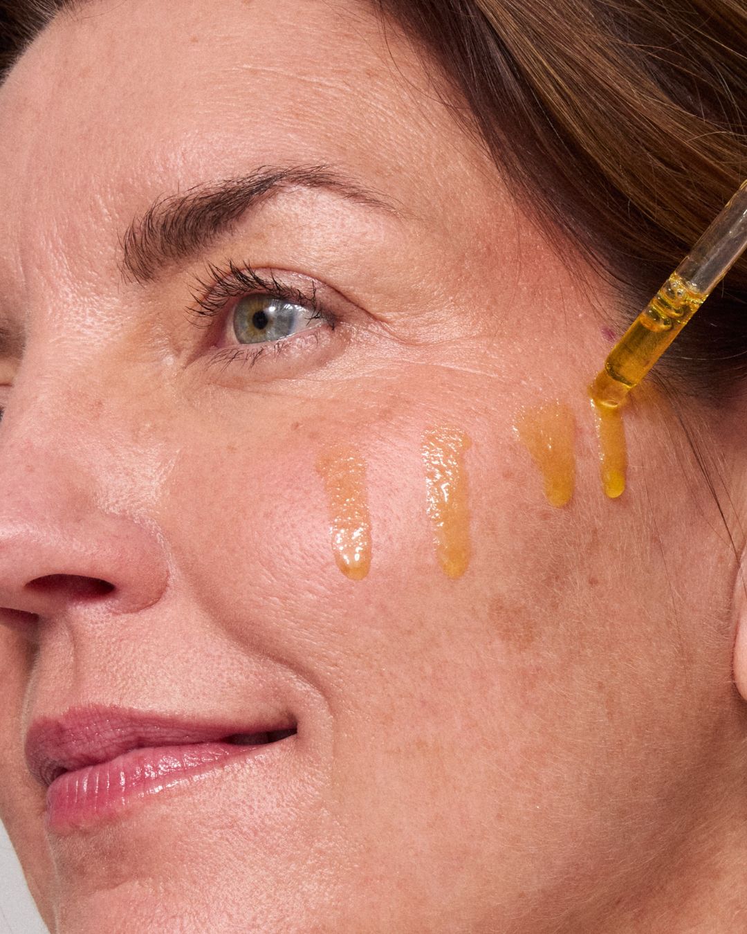 model putting algae retinol oil on her cheeck 